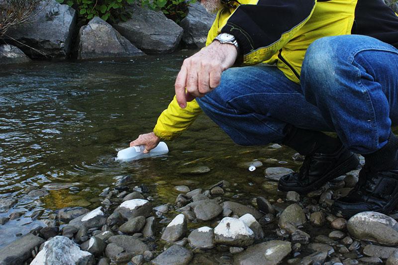 CSI Volunteer James Hamilton gathers a water sample from a point along Six Mile Creek. Back at the lab, CSI scientists will test the water to ensure it meets state regulations.