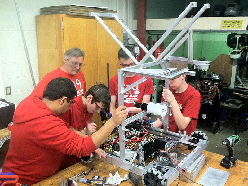 Clockwise from left: Code Red members Akshath Garg, Scott Smith, Ronan Perry and Josh Duell work on putting the robot together Saturday afternoon while mentor Mike Krish looks on in the background.