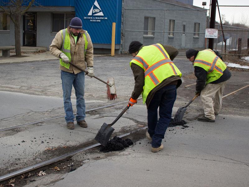 City  workers fill potholes at Cecil Malone Dr.