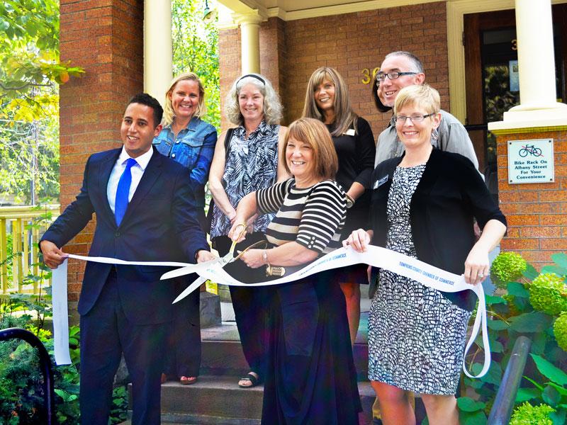 Mayor Svante Myrick and Tompkins County Chamber of Commerce President Jennifer Tevares hold the ribbon while integrative medicine practitioner Margaret Snow cuts it
