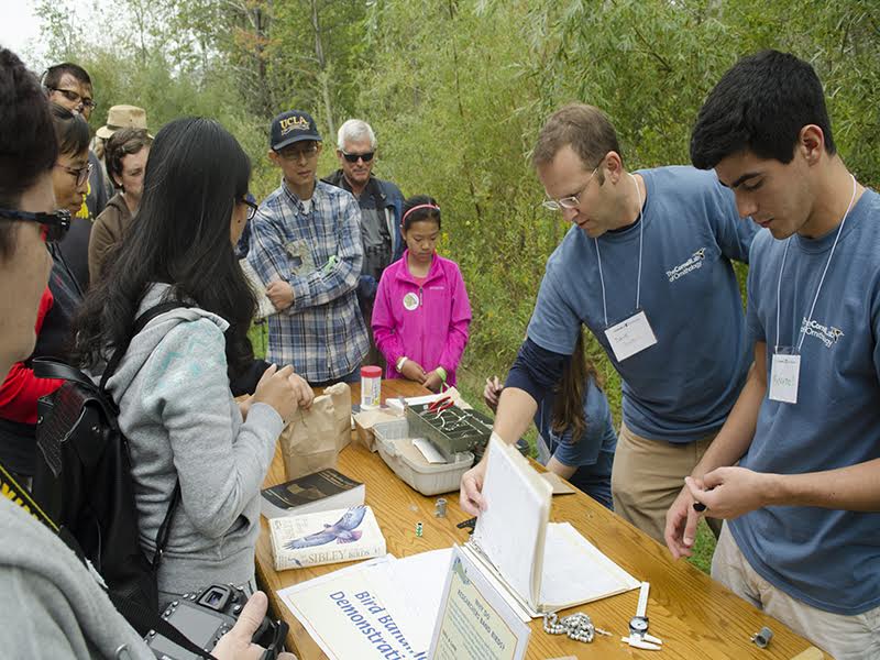 Visitors crowd around a bird demonstration during the Cornell Lab of Ornithology’s Open House