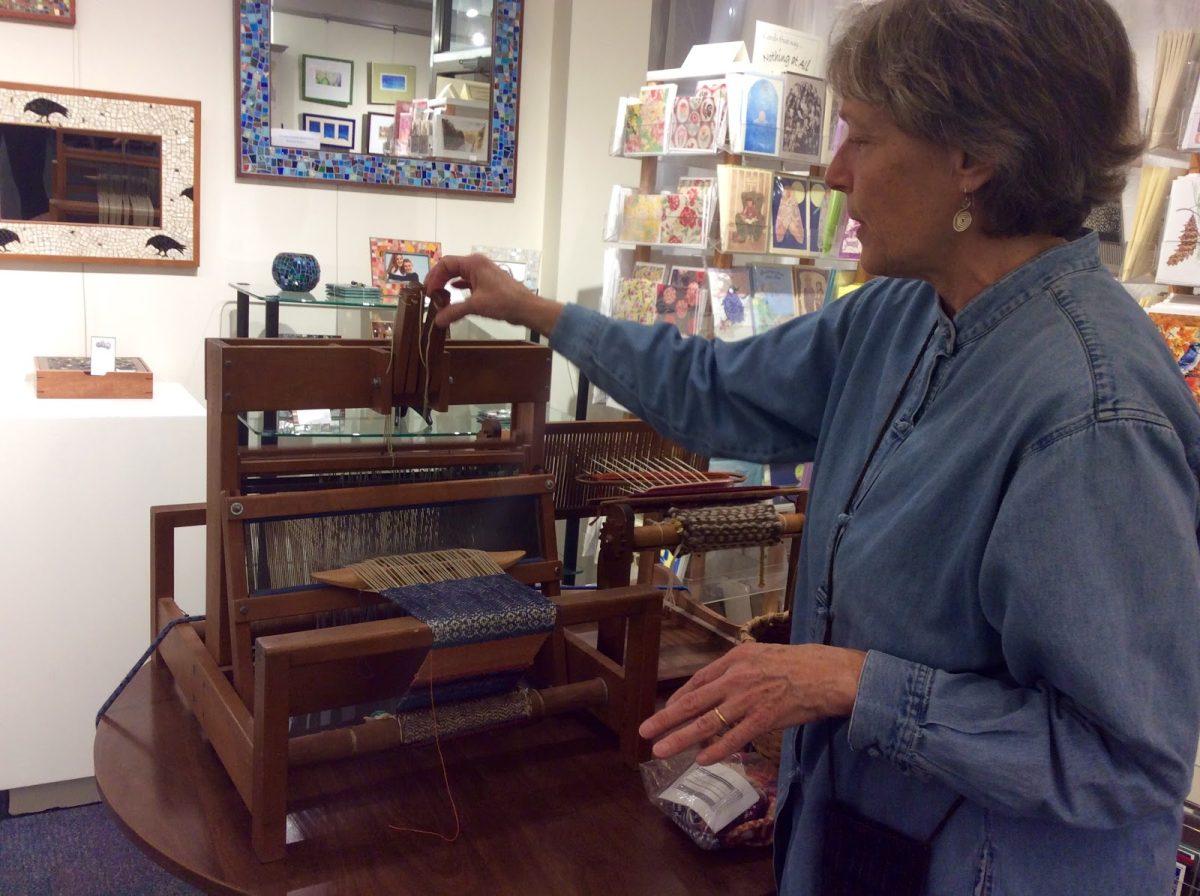 June Szabo demonstrates a weaving technique using her loom at Handwork in the Ithaca Commons
