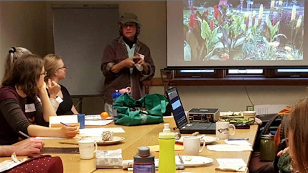 Martha Gioumousis leads the meeting on April 6 by demonstrating to volunteers of the beautification program how to use basic gardening tools.