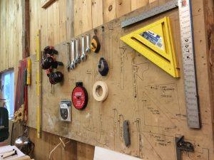 Photo by Christie Citranglo The Hammerstone School: Carpentry for Women’s wall of tools resides above one of the work tables in the studio. Tools ranging from wrenches to saws are mounted on the wall.