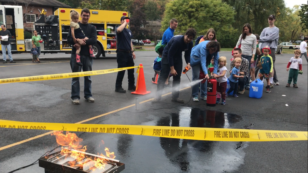 Cornell sophomore Boris Botchev shows children how to extinguish fires at the CHFD Open House using the Bullex, a mock fire tool that can be used for educational and training purposes.