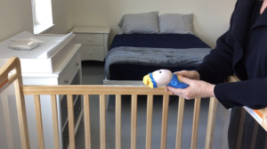 Lee Dillon, Executive Director at TCAction, holding an infant’s toy provided with the crib in an apartment at the Amici House. (Photo by Emily Cartwright/Ithaca Week)