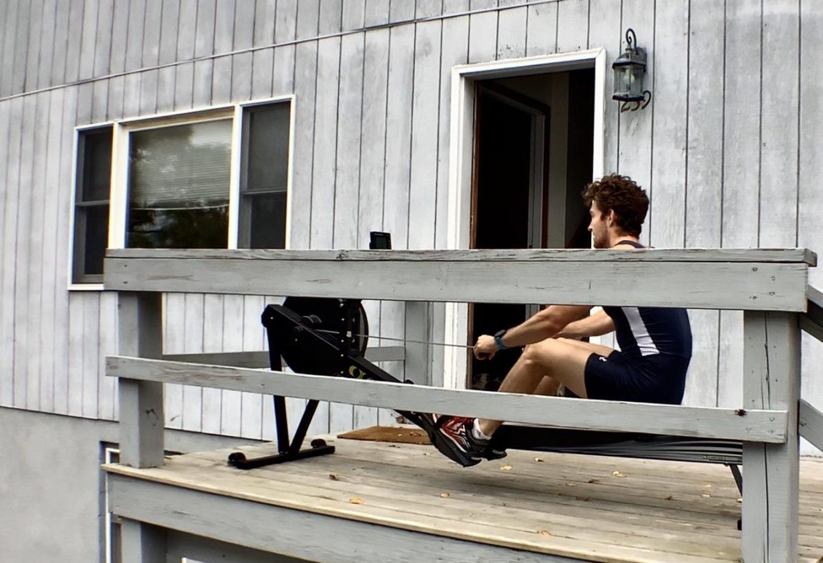 Crew athlete uses rowing machine on porch