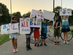 little kids holding signs in support of black lives matter reading 'we are all beautiful,' 'bml' and 'blm'