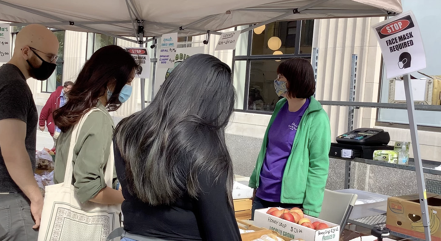 Carrie Natale speaks to customers at the farmer's market, showing them different types of pies.