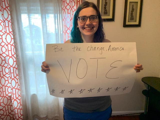 Meg Graff makes a sign to put outside her apartment that reads "be the change, America" to try to encourage people to vote in the upcoming election. (Acacia Krenitsky/Ithaca Week)