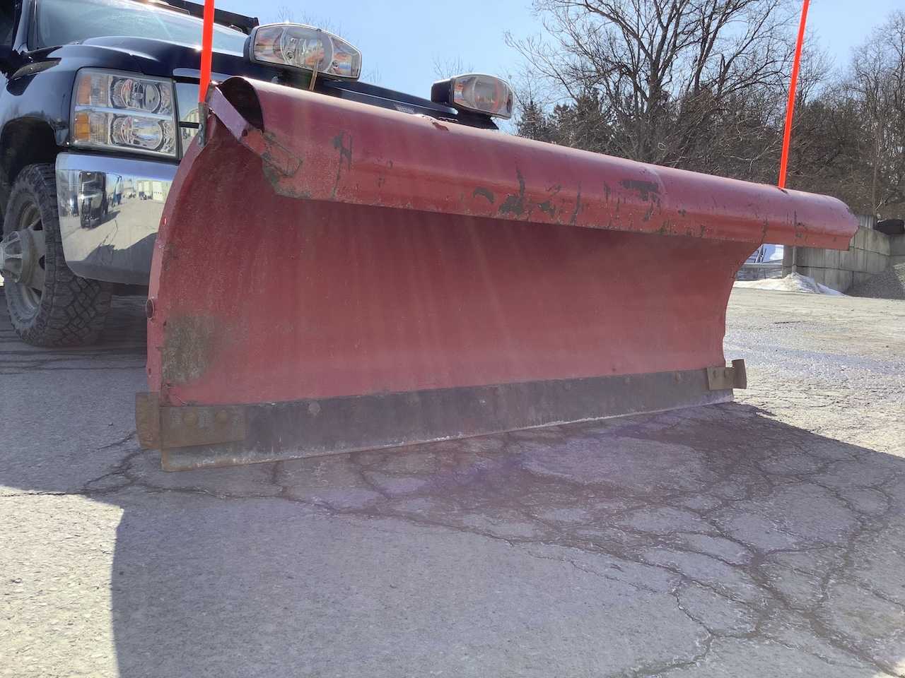 A red plow attached to a blue truck