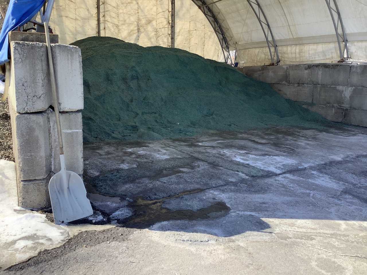 A mound of greenish salt with a shovel in front of it