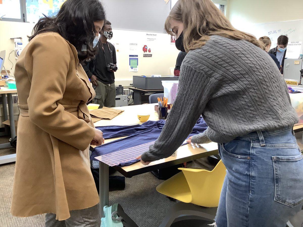 A student and workshop leader lining up the pants of a romper before placing pins for sewing
