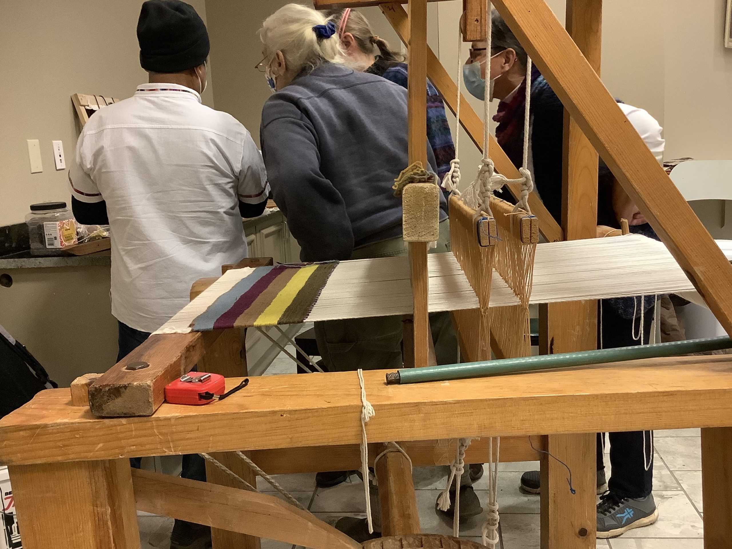 Picture of Gutierréz behind the loom, showing viewers his design for the rug he is weaving.