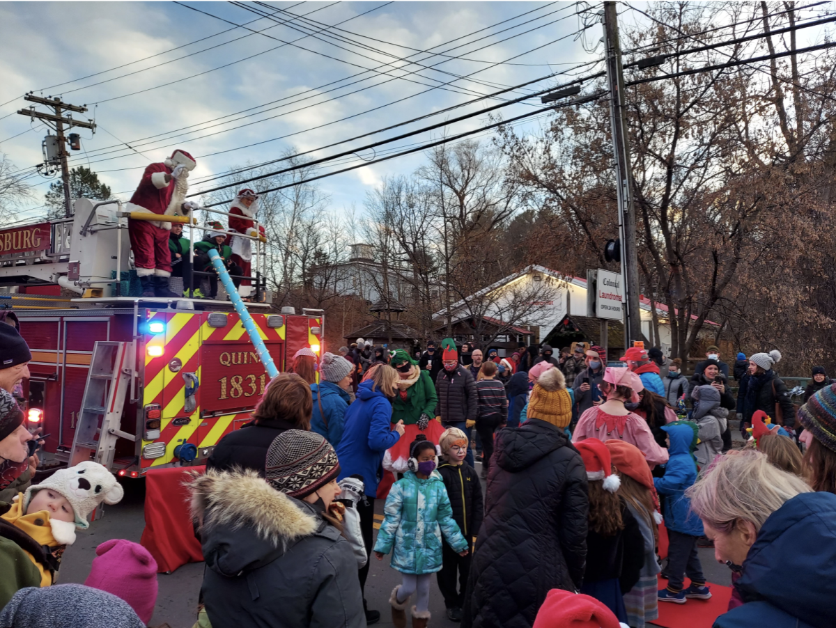 santa stands on top of a firetruck and waves at the crowd
