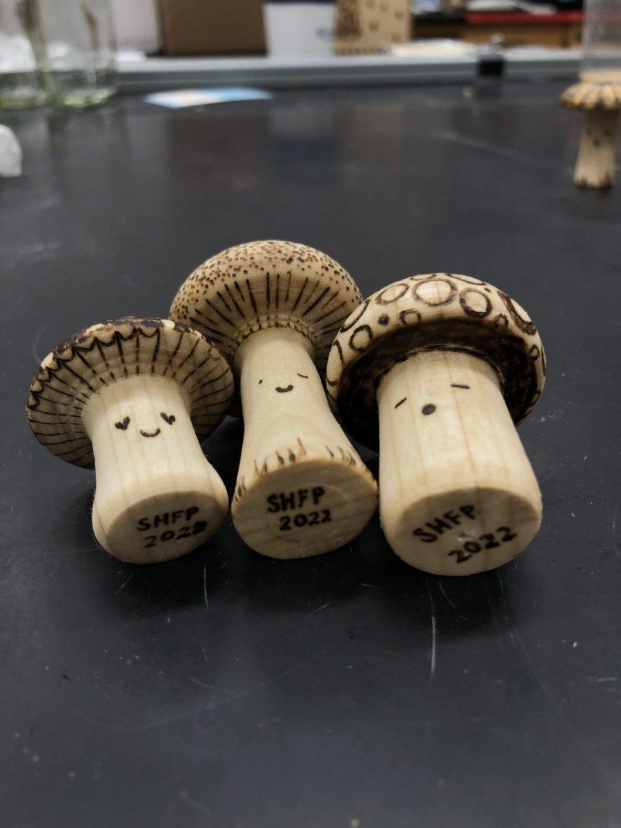 Three wooden mushroom fiurines on a desk.