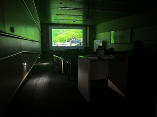 A dark room with a brightly lit up screen display images from the film "When Marnie Was There" for an audience in the foreground.