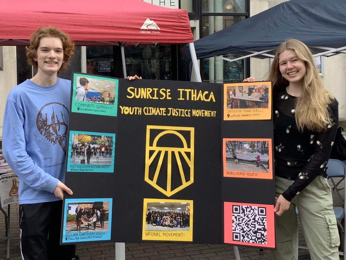 Members Zach Schmitt(left) Linnea Niemack (right) of Sunrise Ithaca display their board to attract youthful climate activists at Earth Day Fest.