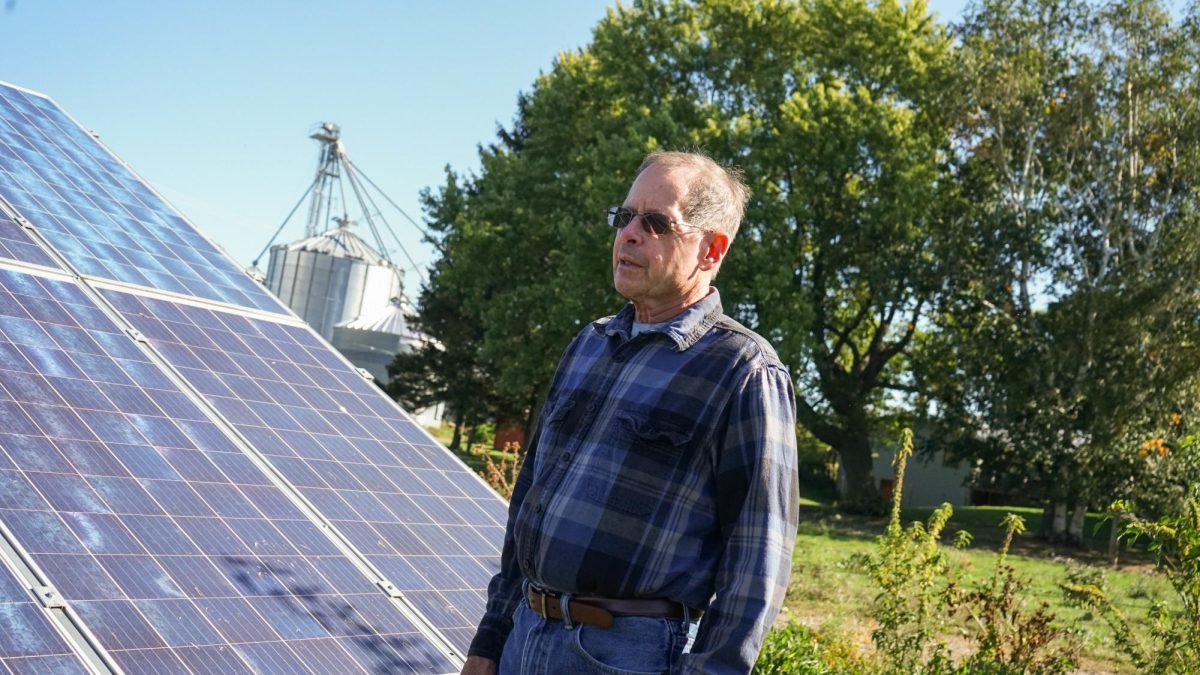 Mike Turner stands beside his row of solar panels sitting on a buffer between his corn fields and cattle pasture. 