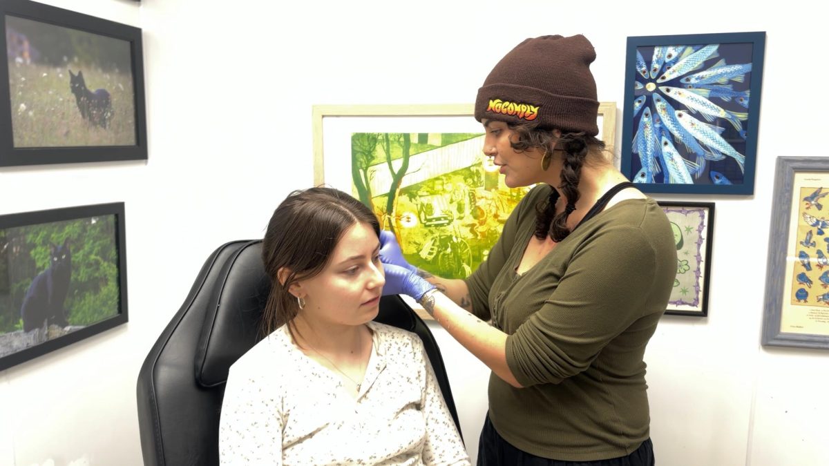 Guest Piercer Mahalia Sol pierces Ithaca College student Lucia Moix’s ears during the Friday the 13th event. 
