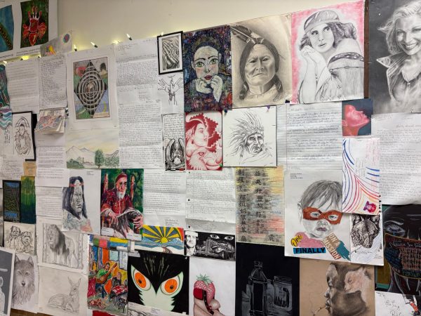A photo of sketches, paintings and written notes posted on a bulletin board.